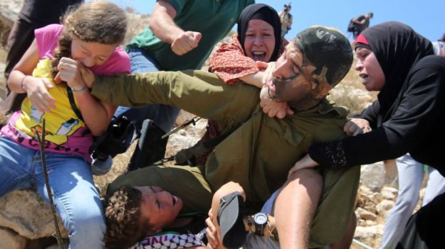 Palestinians try to prevent Israeli soldier from detaining a boy during a protest in the West Bank village Nabi Saleh, August 28, 2015. Reuters